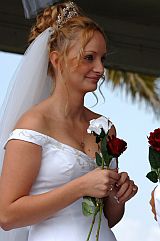 Braut mit Hochsteckfrisur und weisser Rose in der Hand